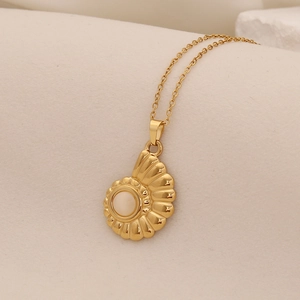 Elegant gold seashell pendant necklace with a white opal gemstone on beige fabric