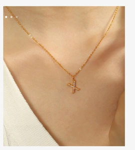 Detail of elegant gold letter X pendant necklace with sparkling stones on female neck