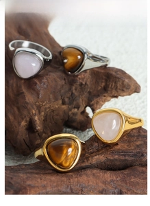 Close-up of vintage natural tiger eye and rose quartz rings on a rustic wood stand