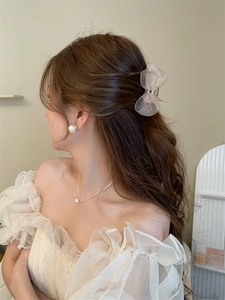 Elegant beige mesh bow hair clip worn by a model with matching pearl accessories