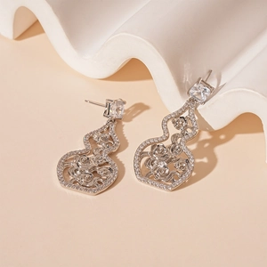 Macro detail of silver hollow gourd earrings with zircon inlay and floral patterns