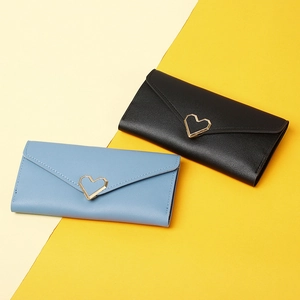 Detail of long tri-fold wallets in black and blue PU leather with heart metal clasp