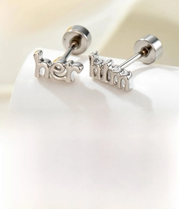 Detailed view of silver titanium steel 'him' and 'her' letter earrings with flat screw back