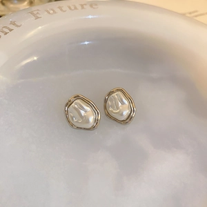 Macro view of French vintage gold geometric earrings with pearl texture on a white tray
