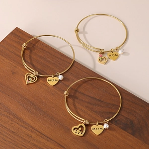 Detailed shot of gold MOM heart charms and pearls on adjustable bangle bracelets