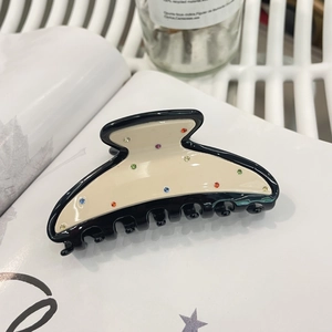 Minimalist acetate hair claw clip with colorful rhinestones on an open book