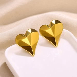 Detailed view of gold-plated geometric heart stud earrings with 3D faceted texture