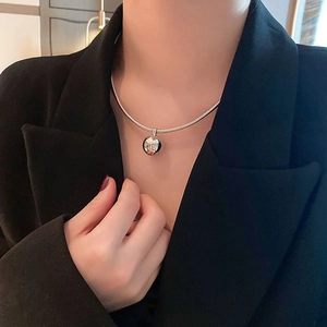 Detail of silver snake chain necklace with a gold petal patterned spherical pendant