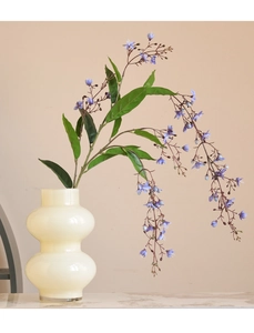 Macro detail of artificial blue jasmine flowers with green leaves in a beige ceramic vase