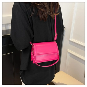 Model showing rose red crossbody bag with adjustable strap over black outfit