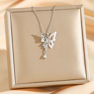 Élégant collier papillon argenté avec pendentif en cristal sur fond de soie champagne