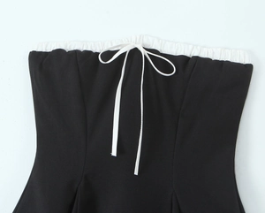 Detail of black tube top featuring white ruffled trim and a delicate bow tie decoration