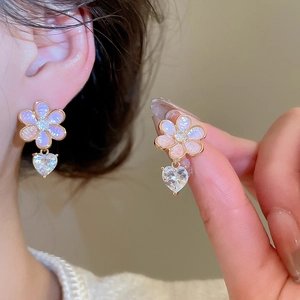 Close-up of pink flower earrings with heart zircon pendant on a model's ear