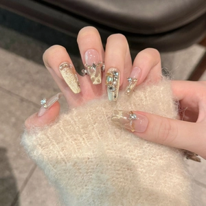 Detail of luxury gold cat-eye press-on nails with sparkling rhinestones and metal accents