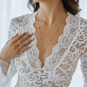 Close-up of gold Y-necklace with multicolor heart stones and slave bracelet on model