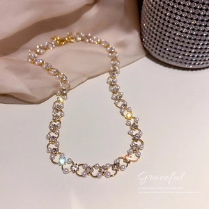 Détail d'un collier doré de luxe orné de perles blanches et de zircons scintillants