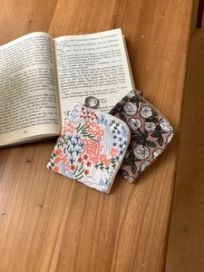 Close-up of floral embroidered linen coin purses on a rustic wooden background