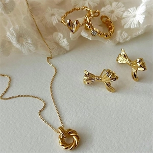 Detailed set of gold plated jewelry with heart ring and bow earrings on lace