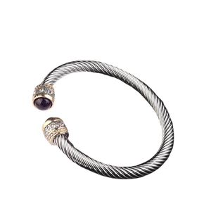 Silver cable cuff bracelet with gold accents and purple stones on a white background