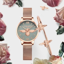 Close-up of rose gold watch with grey bee dial and matching bee cuff on rose petals