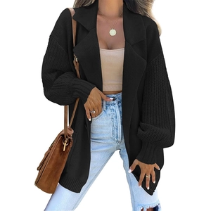 Detail of black knit cardigan featuring wide lapels and textured chunky knit sleeves