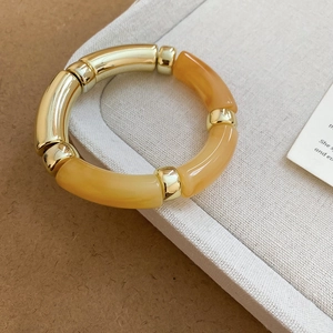 Détails du bracelet en acrylique marbré ambré et métal doré sur un support minimaliste