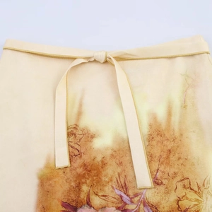 Détail de la taille d'une jupe midi florale avec cordons et motifs abstraits tons chauds