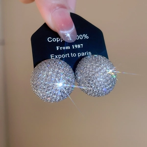 Gros plan de boucles d'oreilles dôme en cuivre serties de zircons étincelants
