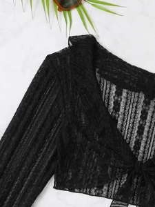 Close-up of black lace cover-up featuring delicate hollow-out details and vertical texture