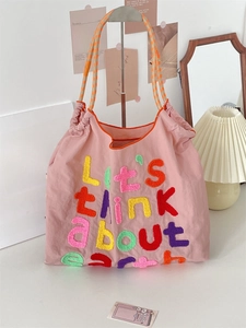 Detail of pink canvas tote bag with chenille embroidery and orange woven rope handles