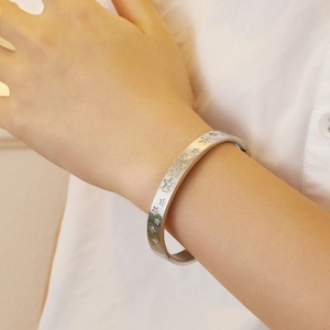 Silver star engraved titanium steel bangle with zircon stones on a model's wrist