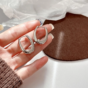 Close-up of polished silver U-shaped hoop earrings with a minimalist mirror finish