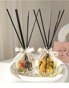 Detailed view of glass reed diffusers with dried flowers and black scent sticks