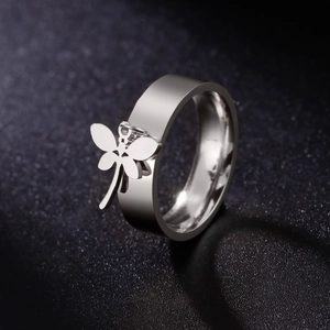 Polished stainless steel ring featuring a hanging dragonfly pendant on dark background