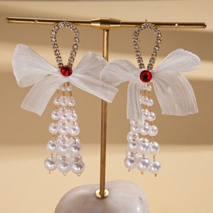 Detail of chiffon bow earrings with pearl tassels, rhinestones and red stones on a stand