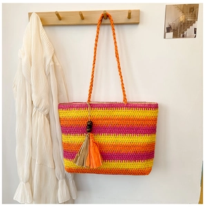 Detail of colorful rainbow striped straw tote bag with decorative tassel on wooden hook