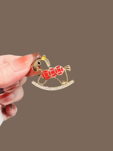 Close-up of a rocking horse brooch with red enamel patterns and sparkling rhinestones