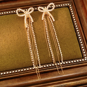 Detailed macro view of 18k gold plated bow earrings with long shimmering zircon tassels