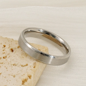Close-up of a brushed titanium steel wide band ring resting on a natural porous stone