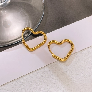Macro shot of polished gold heart-shaped hoop earrings with smooth metallic finish