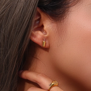 Detail of gold-plated Mom ring and soda cup earrings with pink stones worn by model