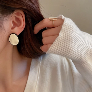Boucles d'oreilles dorées et bague en T avec strass sur mannequin en émail crème
