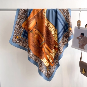 Detail of luxury silk scarf with blue and orange geometric prints hanging on a hanger