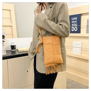 Detail of camel suede tote bag with long fringe accents and a stylish knotted shoulder strap