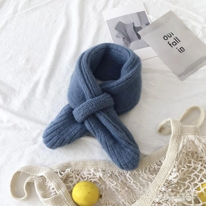 Detail shot of blue chunky knit baby scarf with cross-loop design on white fabric