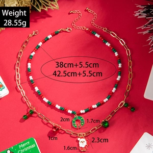 Detailed view of beaded Christmas necklace set with Santa and wreath charms on red background