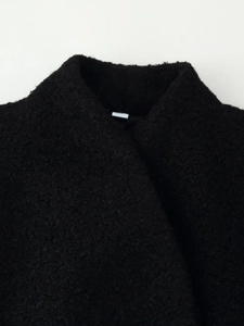 Close-up of black thickened wool coat showing plush texture and lapel design details
