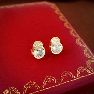 Detailed shot of gold-plated stud earrings with pavé zircons on a luxury red gift box