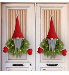 Close-up of lighted Christmas gnome wreaths with warm LED lights on a white door