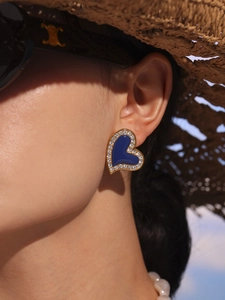 Close-up of model wearing heart-shaped blue enamel earrings with sparkling cubic zirconia